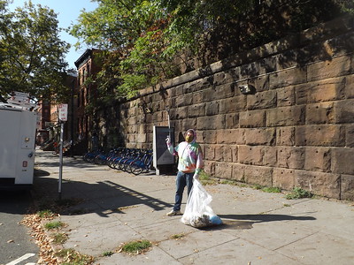 Person holding trash bag next to the Embankment wall near the Coles St. Citi Bike station